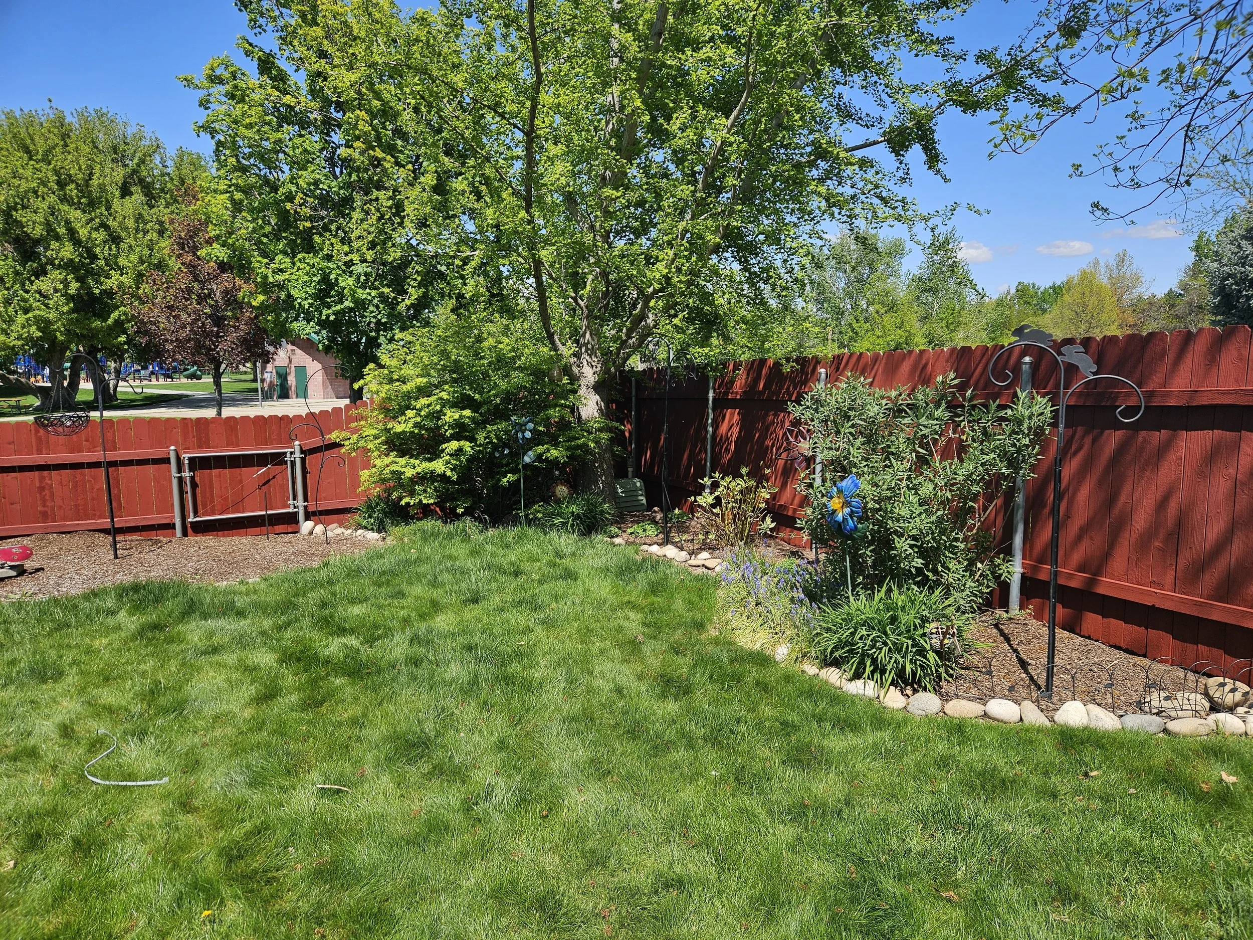 Red solid-stain fence finish around a manicured lawn